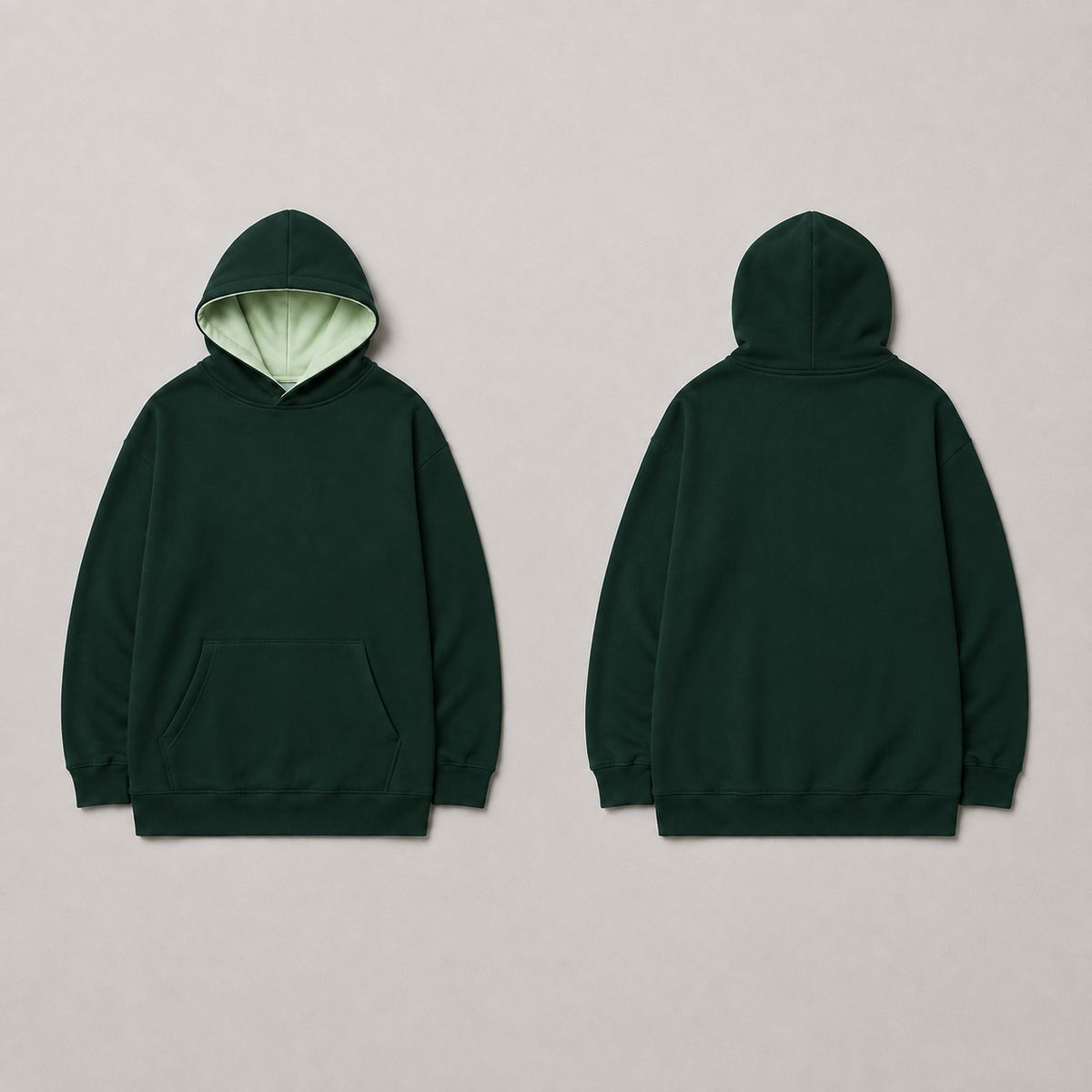 Front and back of the same broad hoodie in dark pine green with pale celadon hood lining.