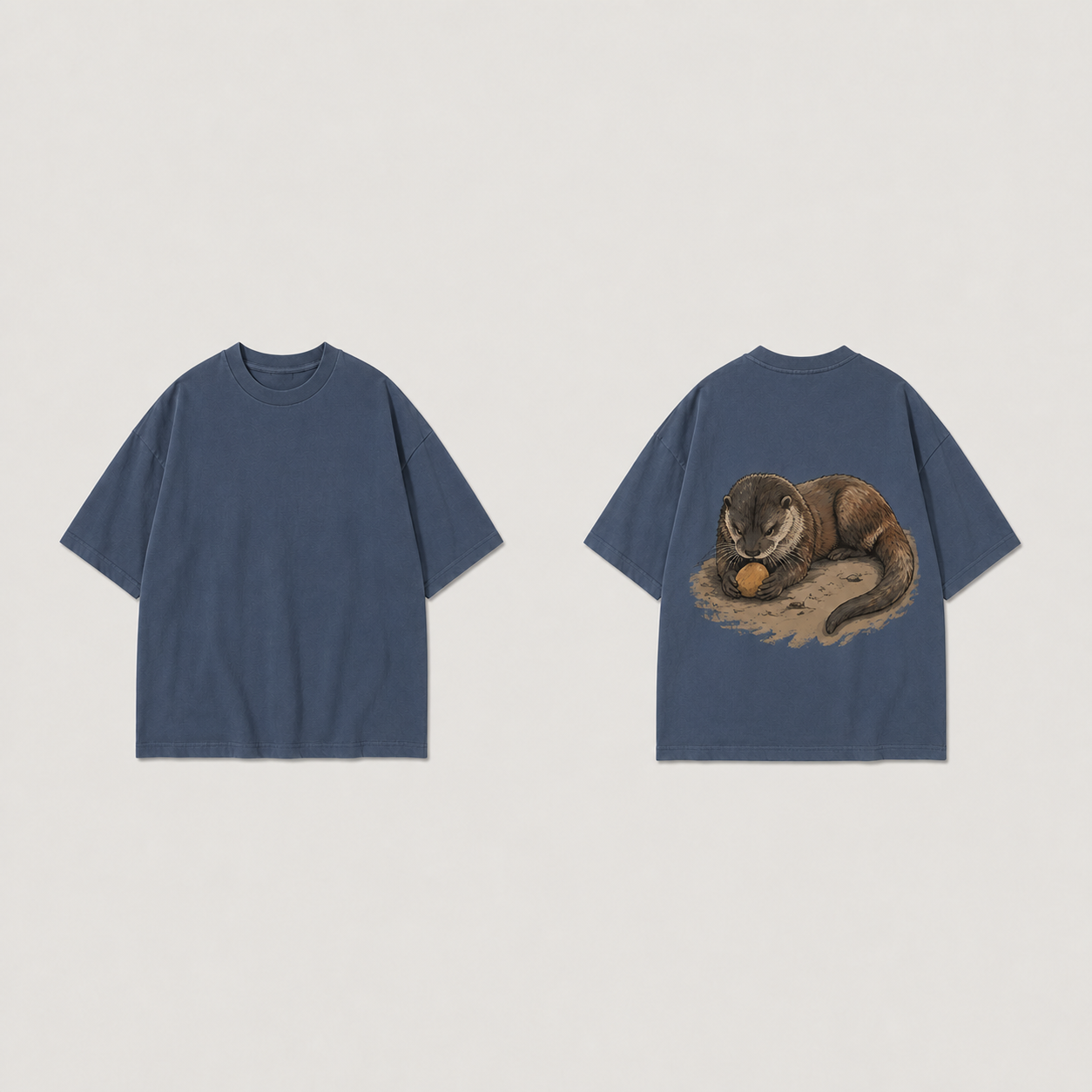 Front and back of a lead blue oversized tee, plain on the front, with one otter holding an ochre stone between its forepaws on the back.
