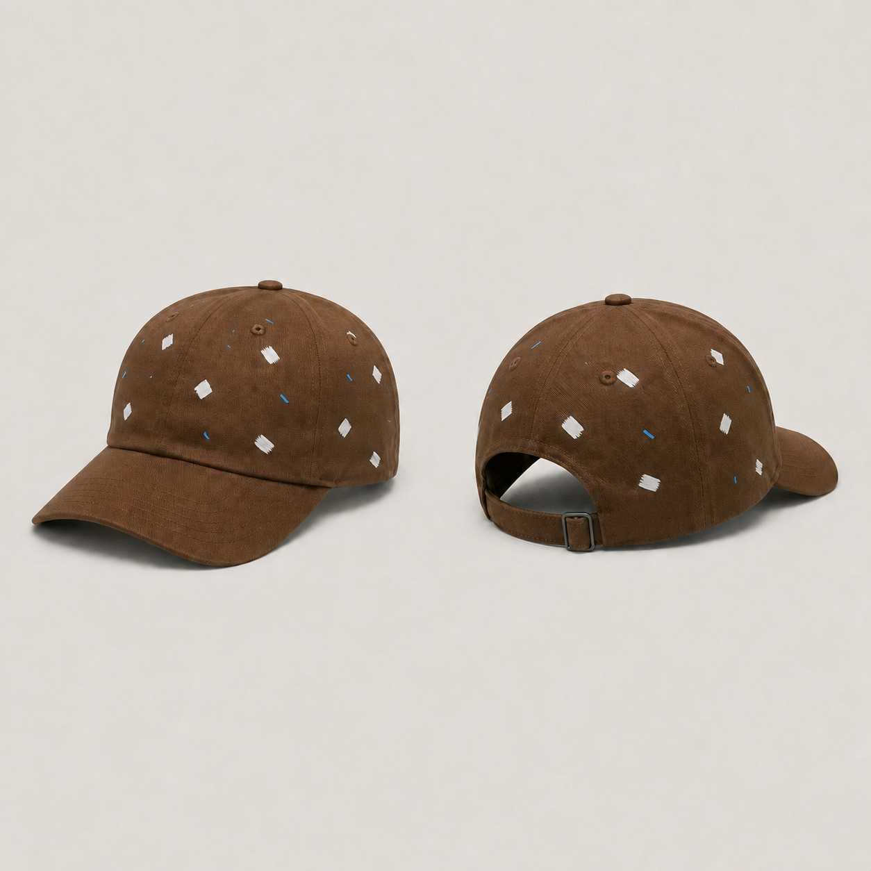 Front and back three-quarter views of a tobacco-brown cap with scattered chalk brush lozenges and fine blue dashes, a plain peak and one rear buckle strap.
