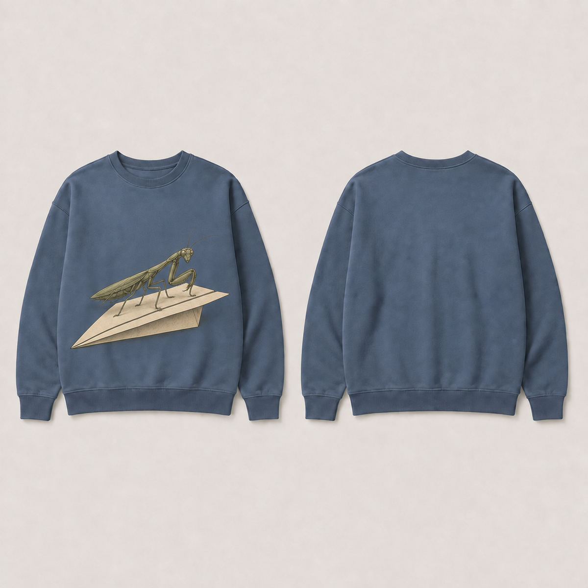 Front and back of a dusk-blue crewneck; the front shows an olive praying mantis standing on a cream paper airplane, and the back is plain.