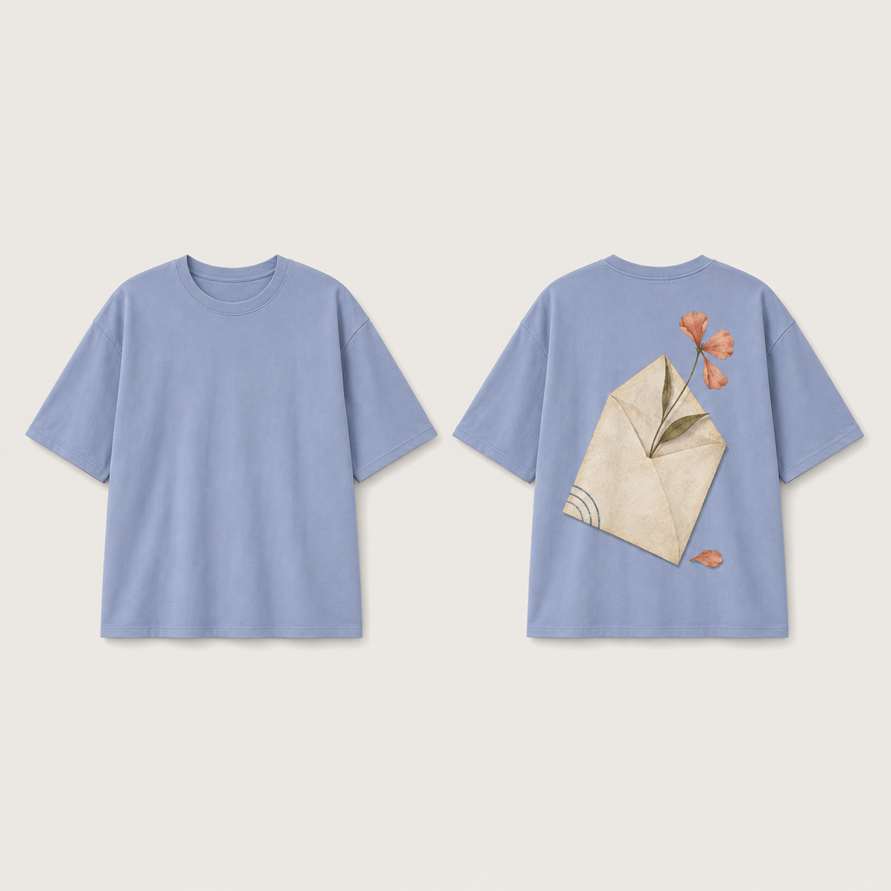 Front and back of a dusty-cornflower oversized tee; the plain front contrasts with a diagonal cream envelope, coral pressed flower, fallen petal and blue curved marks on the back.