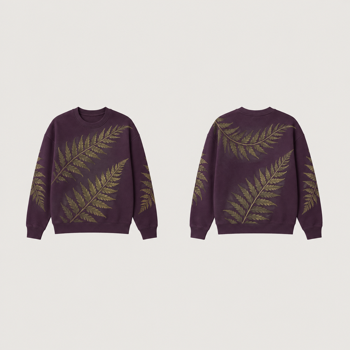 Front and back of a deep-plum crewneck with large diagonal moss-green fern-like fronds across the body and sleeves, and plain plum ribs.