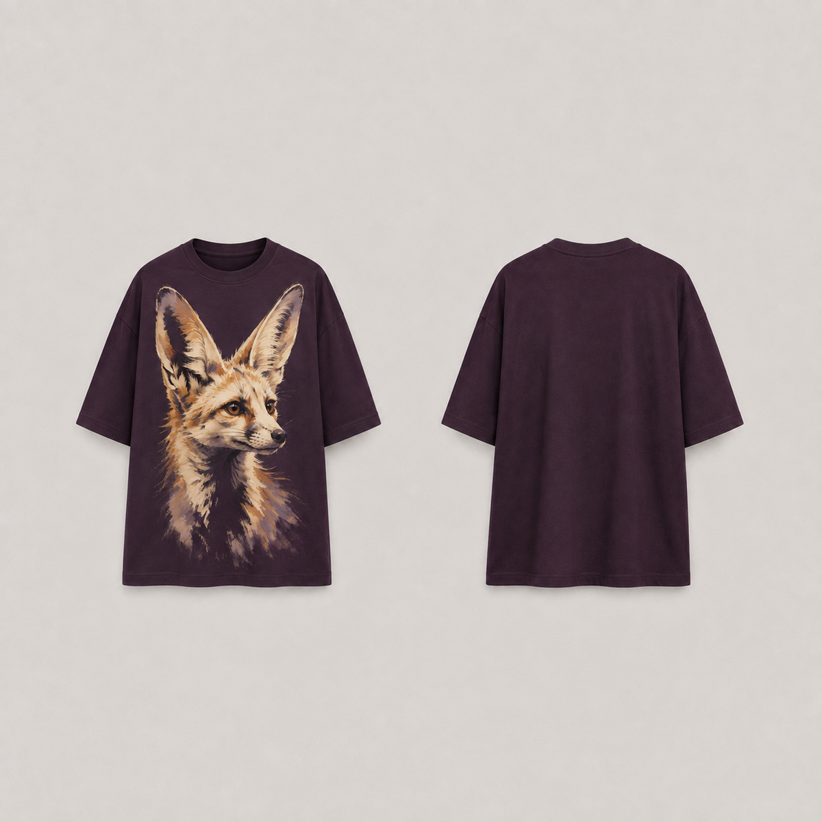 Front and back concept views of an aubergine oversized tee with a large cream-and-rust fox portrait and upright ears on the front; back and sleeves plain.