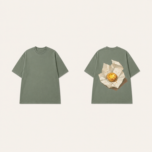 Front and back of an Eucalyptus oversized tee, with a golden custard tart inside expansively opened pale bakery paper on the back.