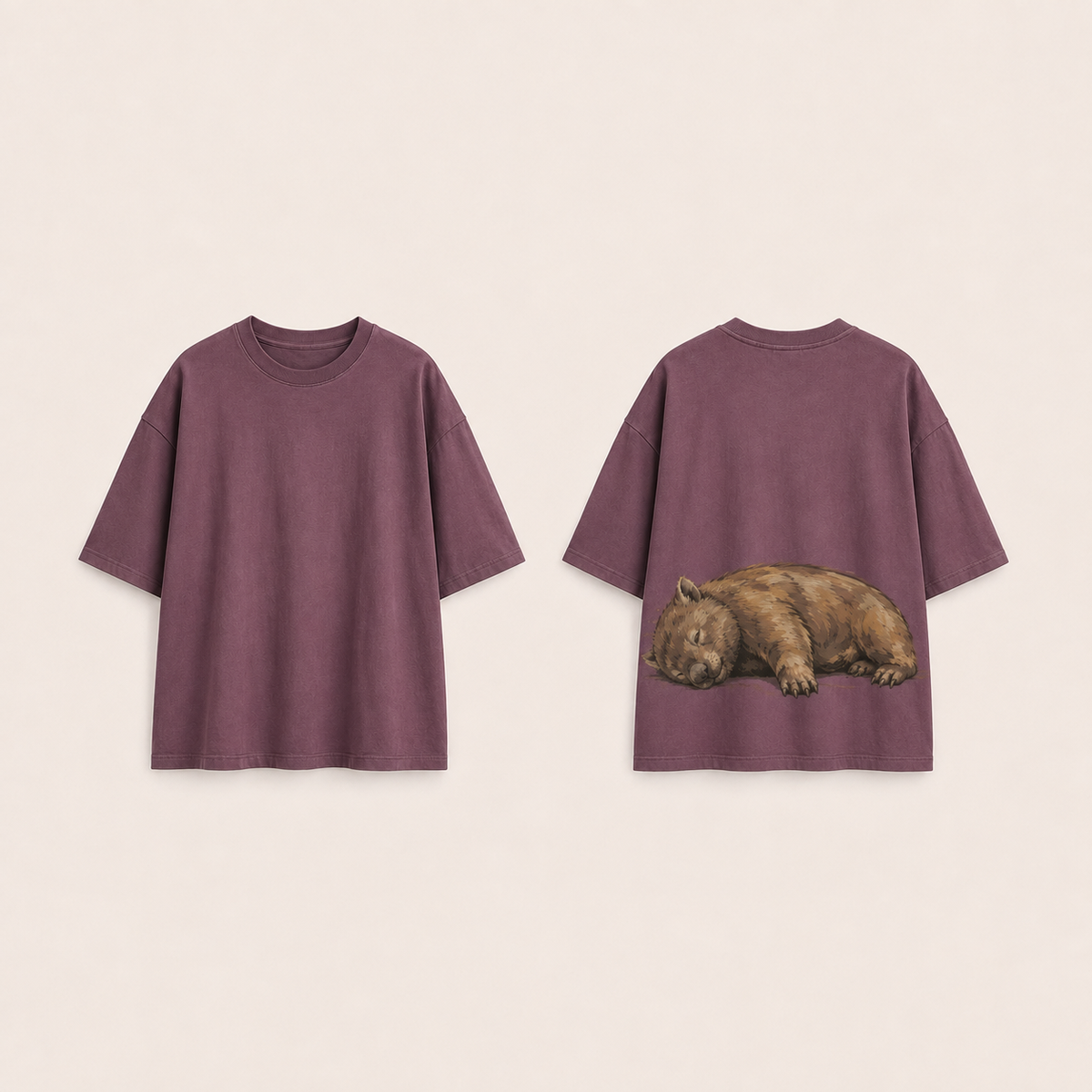 Front and back concept views of a faded-plum oversized tee with a plain front and a broad ochre wombat resting on its side across the back.