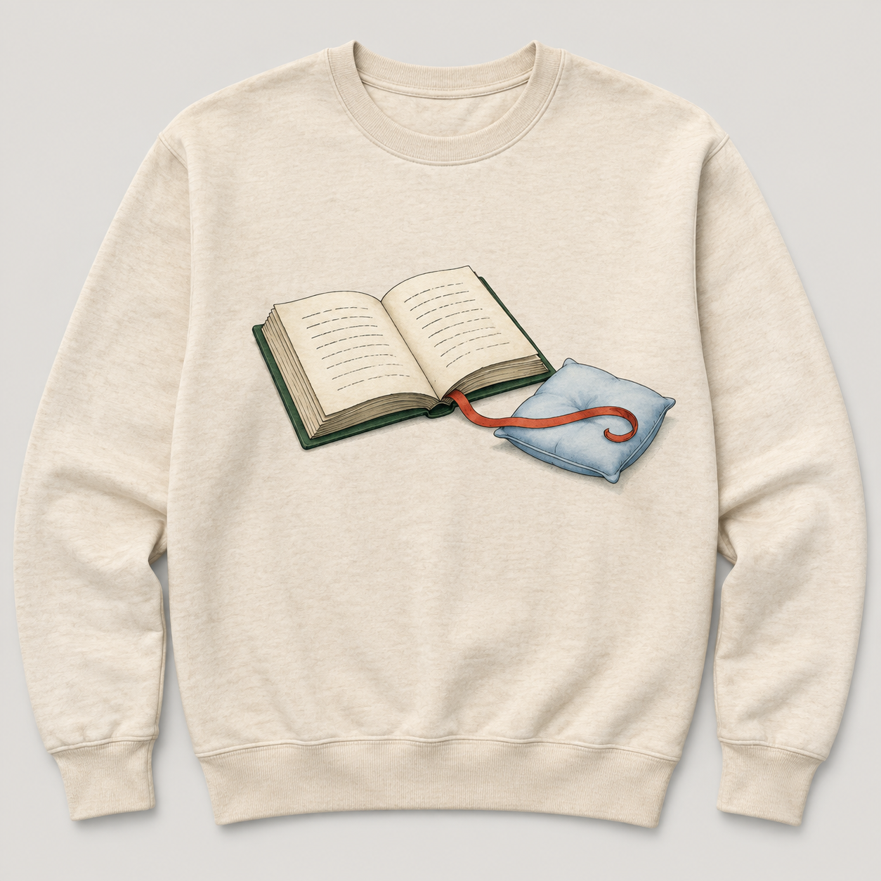 Oatmeal crewneck design with an open green book and a red ribbon bookmark resting on a tiny blue pillow.