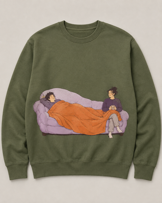 Moss-green crewneck design showing two people sharing a lilac sofa and an unevenly shared orange blanket.